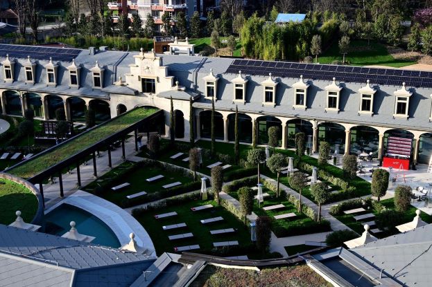 Veduta aerea del parco termale esterno delle Terme De Montel a Milano con giardini curati, lettini, piscina e tetti con pannelli solari.
