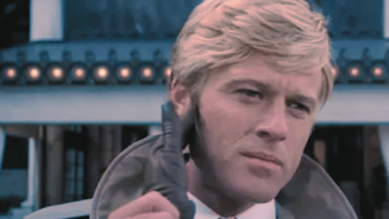 Robert Redford in una scena del film I tre giorni del Condor (1975), con trench e sguardo intenso.