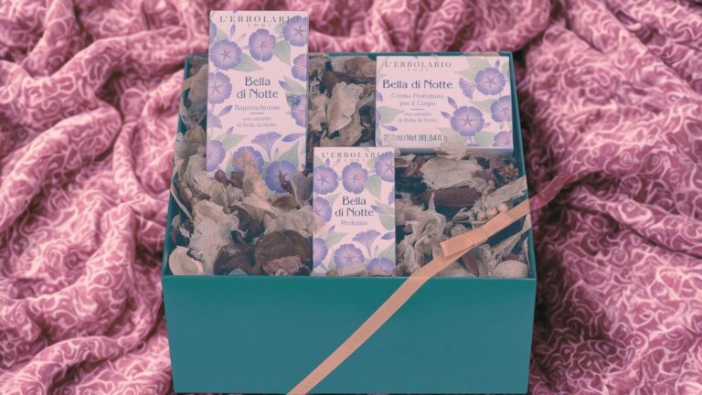 Cofanetto regalo L’Erbolario Bella di Notte con bagnoschiuma, profumo e crema corpo in confezioni floreali, presentato in una scatola verde acqua su fondo di tessuto rosa.
