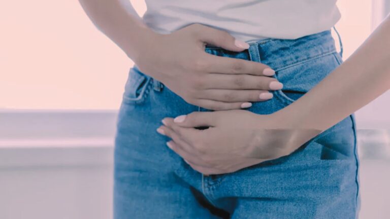 Persona con le mani sull’addome inferiore, gesto che suggerisce dolore o fastidio alla vescica.