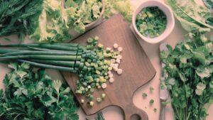 Erbe aromatiche fresche e cipollotti tagliati su tagliere