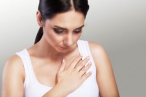 Donna con mano sul petto che indica dolore o fastidio toracico