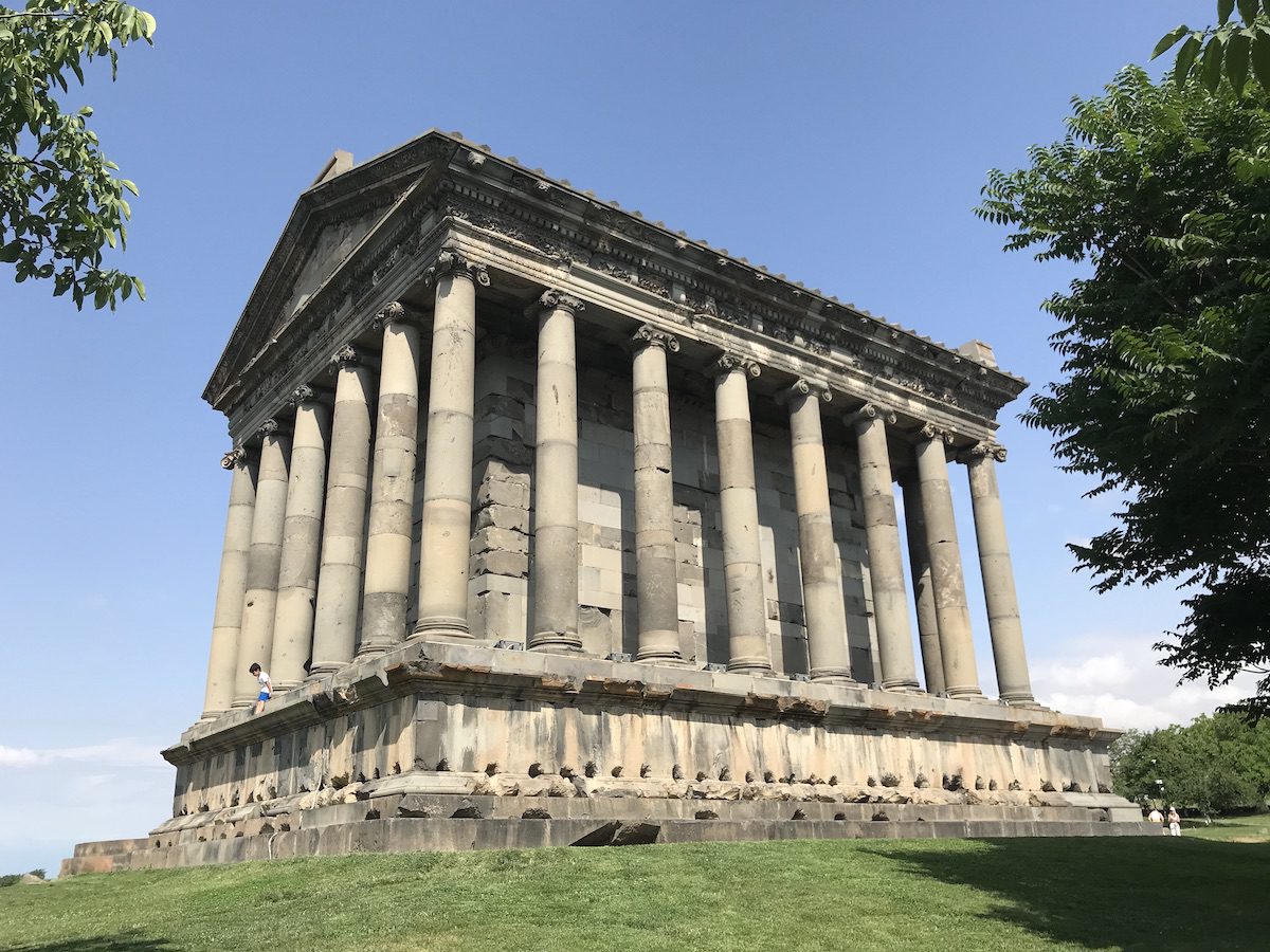 Tempio di Garni in Armenia, edificio di epoca ellenistica con colonne in pietra, circondato dal verde.
