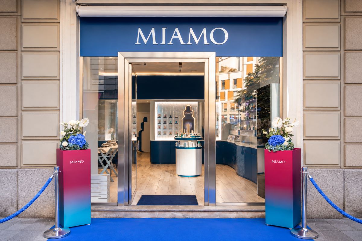Ingresso di CASA MIAMO a Milano, con insegna del brand, vetrine aperte e allestimento floreale nei colori blu e bianco.