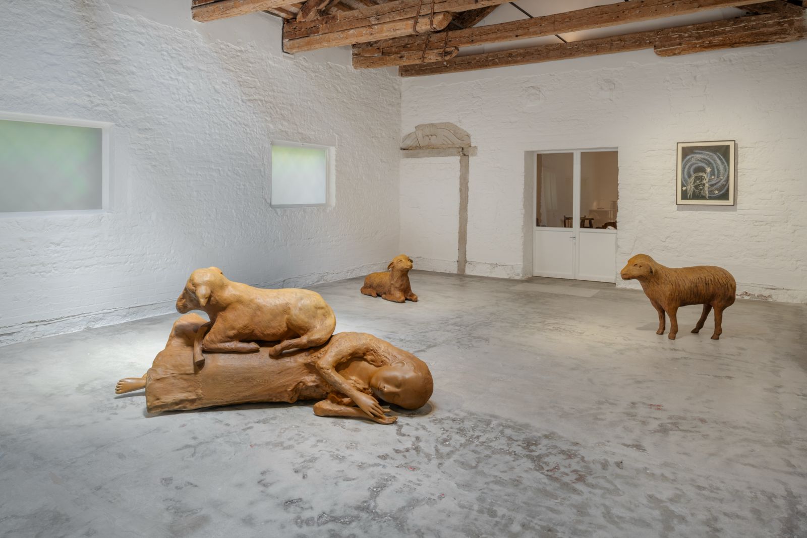 Sculture di Kiki Smith raffiguranti figure femminili e agnelli, esposte in una galleria veneziana con pareti bianche e travi in legno a vista